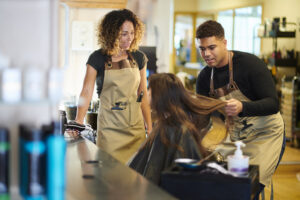 Two cosmetologust students workign aon a clients hair in the salon.