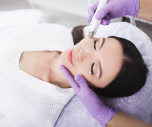 an esthetician applying a facial to a client who is laying on a table.