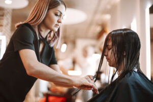 a cosmetologist cutting a clients wet hair in a salon.