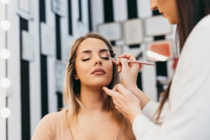 a cosemtologist applying eye makeup to a client.