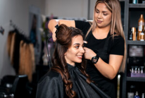 a cosmetologist curling a clients hair.