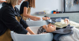 Two hairdressers washing two clients' hair at the hair salon.