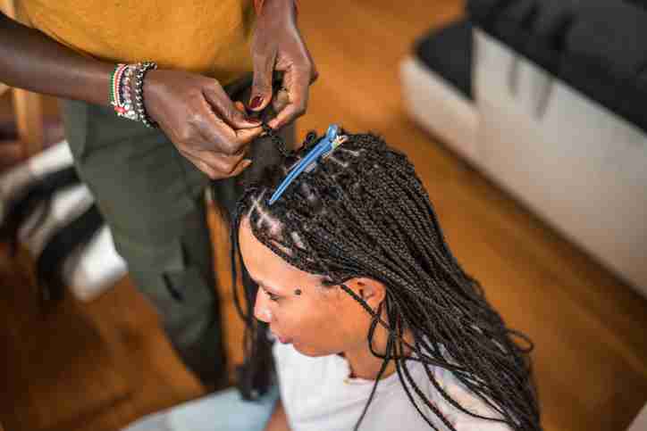 A women braiding another women's hair in tiny braids.