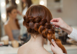 a cosmetologist braiding a clients hair.