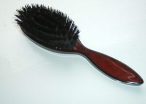A brown and black hairbrush lying on a table.