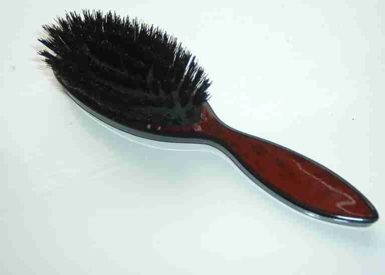 A brown and black hairbrush lying on a table.