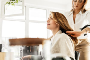A hairdresser dry cutting a clients hair in a salon booth.