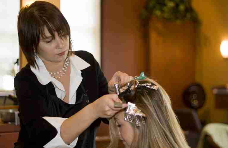 A hairdresser adjusting the foil in a clients hair who is dying their hair blonde.