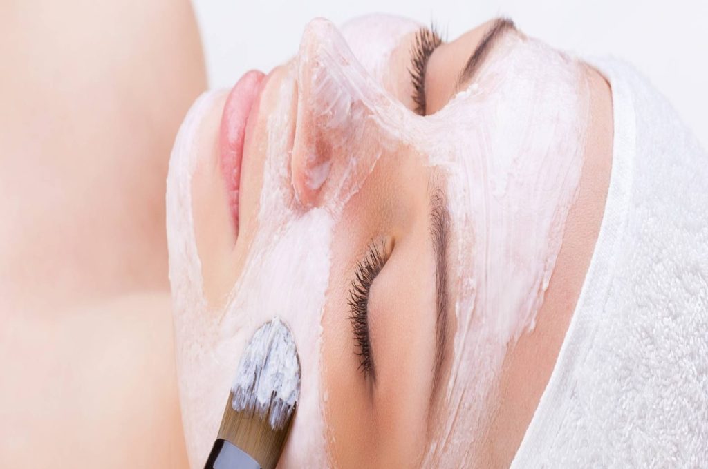Esthetician student applying a facial treatment to a client in a serene spa setting at Avenue Five