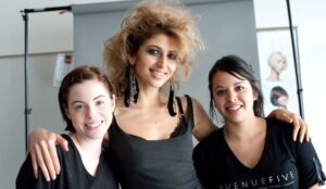 A model standing between two Avenue Five Institute students who just did her makeup and hair.