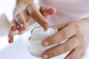 A close up picture of a person taking cream from a jar.