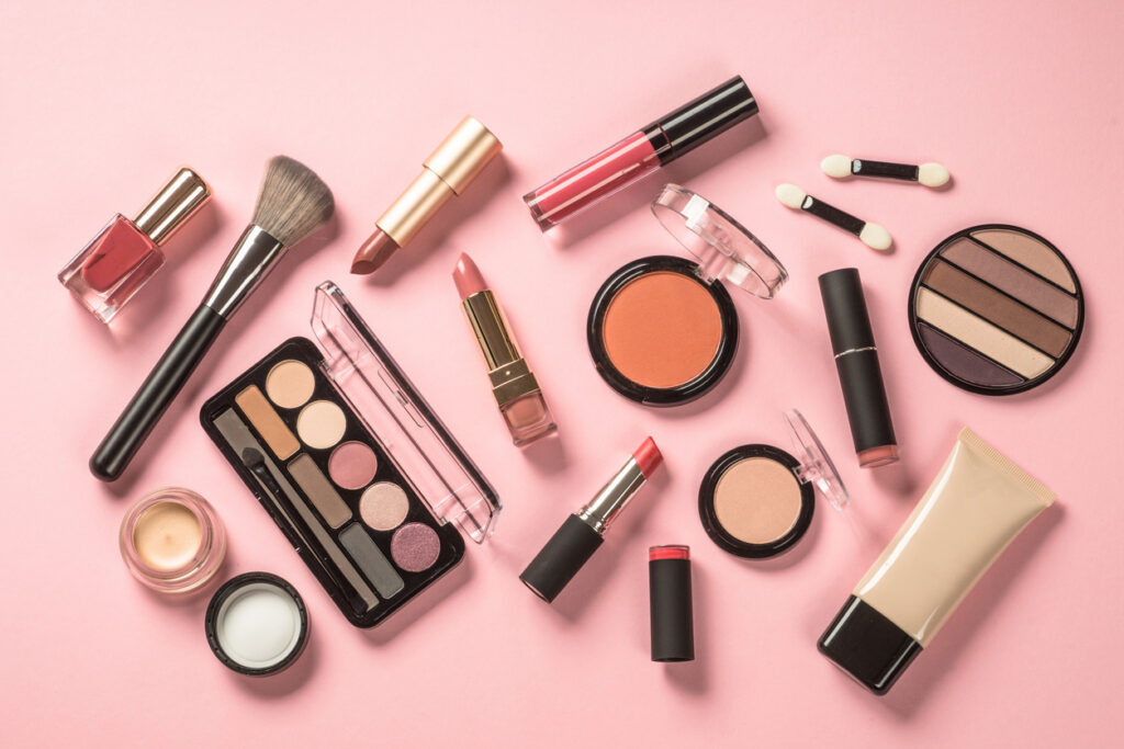 I pink background with various makeup products on display.
