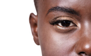 A zoomed-in image of a woman's eye who has glittering gold eyeshadow applied.