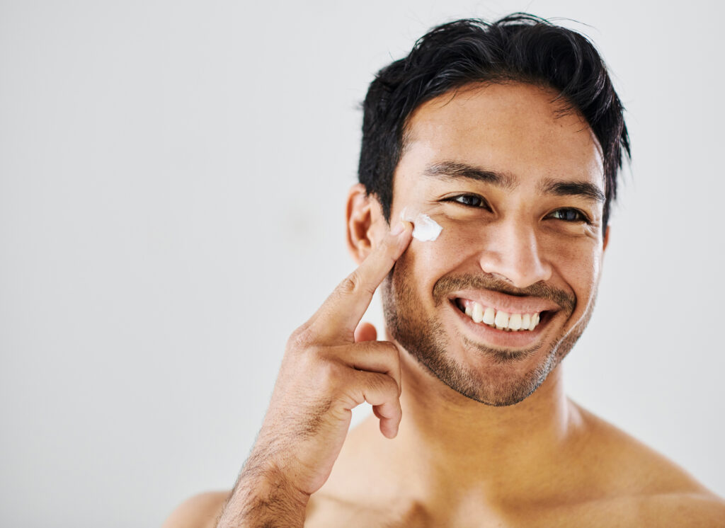 A profile image of a man applying face cream to his cheek.