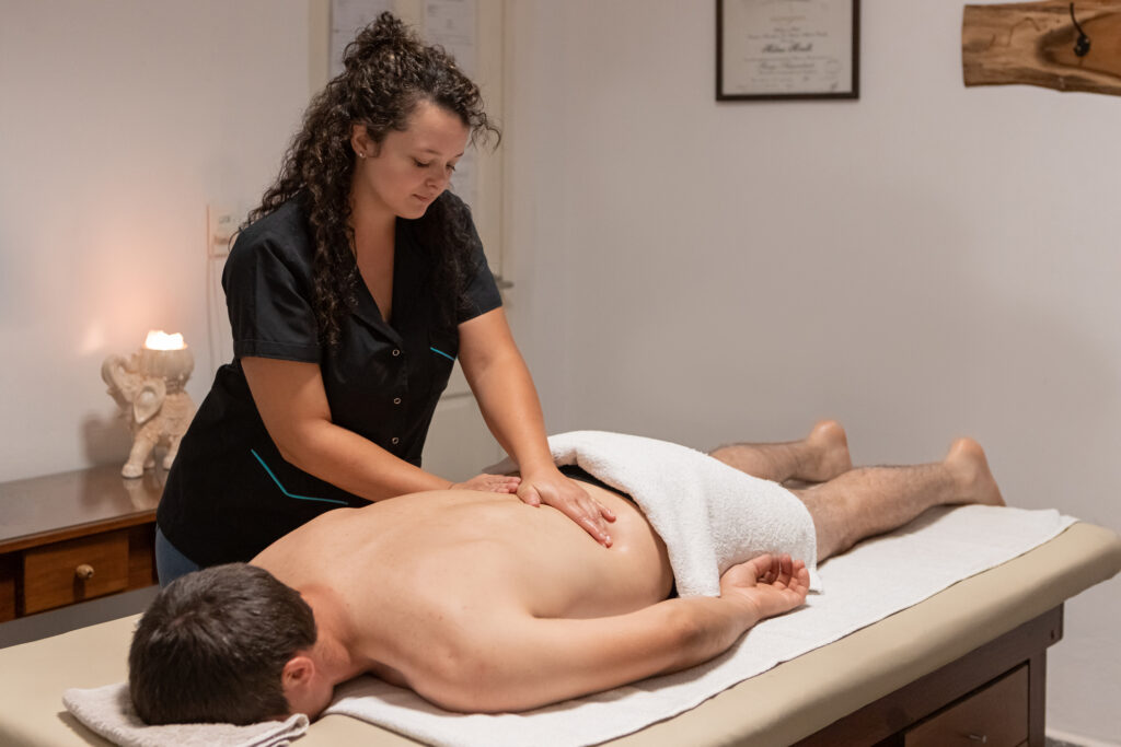 A man lying on a massage table with a massage therapist massaging his back.