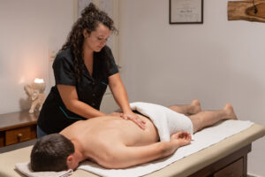 A man lying on a massage table with a massage therapist massaging his back.