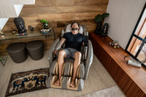 A man laying back in a full body massage chair.