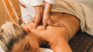 A woman lying on a massage table receiving a deep tissue massage.