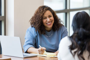 A woman helping a student fill out paper work.