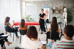 A massage therapist instructor teaching a classroom of students massage therpay.