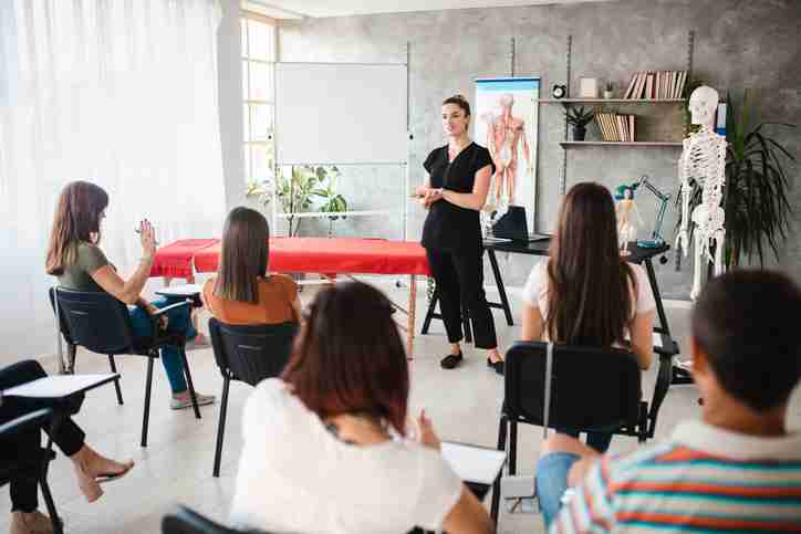 A massage therapist instructor teaching a classroom of students massage therpay.