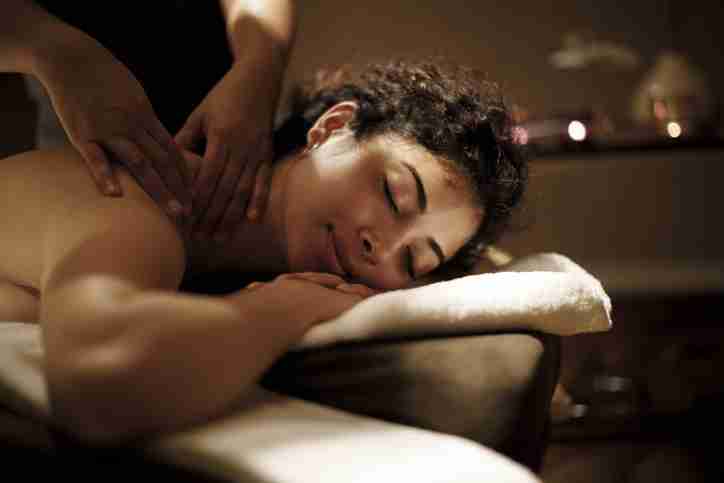 A woman lying on a massage table receiving a deep tissue massage.
