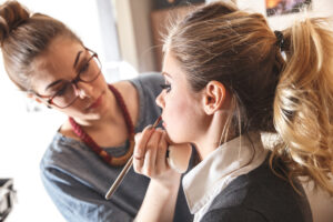 A makeup artist is doing a woman's makeup.