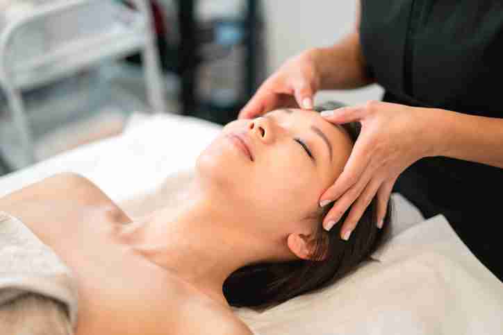 A massage therapist giving a client a head massage.