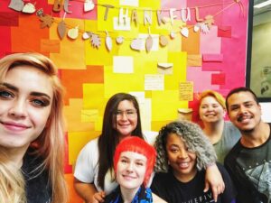 A group of students smiling for the camera in front of a Thanksgiving sign.