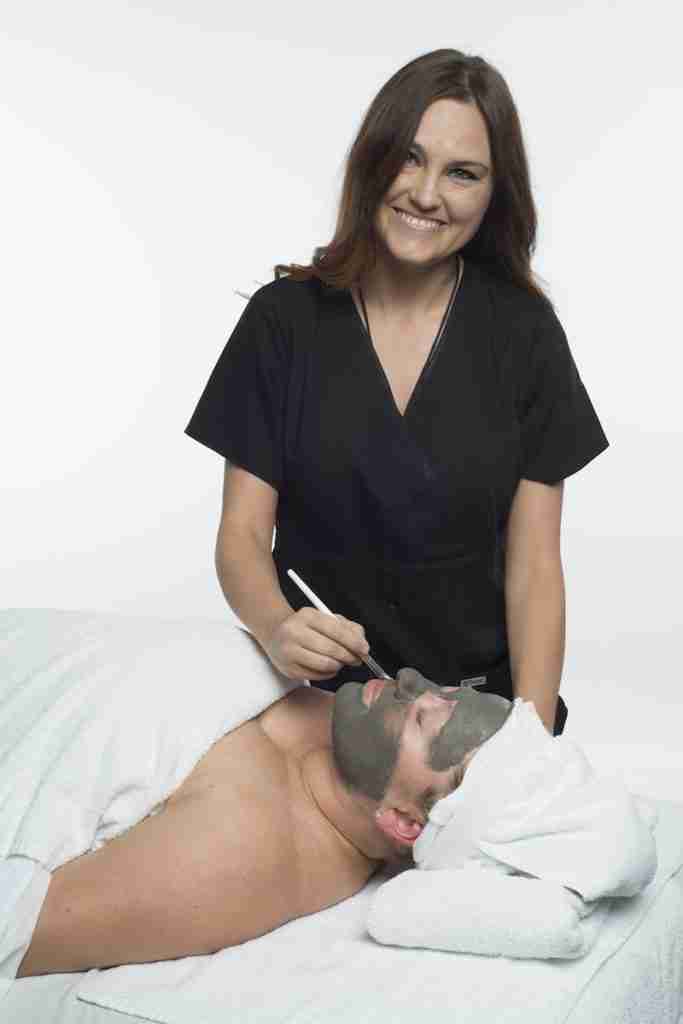 An esthetician applying a facial to a client's face.