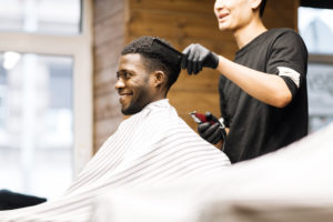 Barber styling client's hair while chatting and laughing