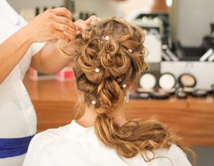 Cosmetologist student styling a clients hair with hair accessories.