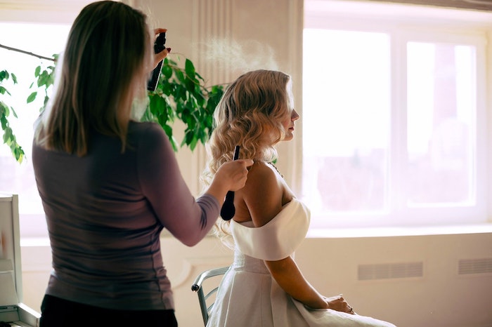 Cosmetology Industry - self-employed cosmetologist works on bride's hair before wedding