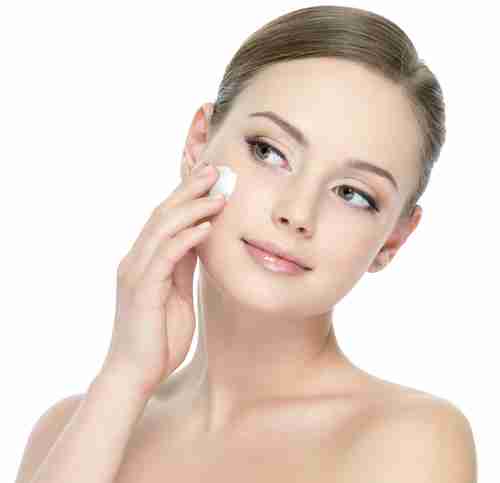 a woman applying product to her face