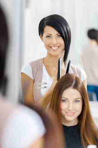A hairstylist straightening clients hair