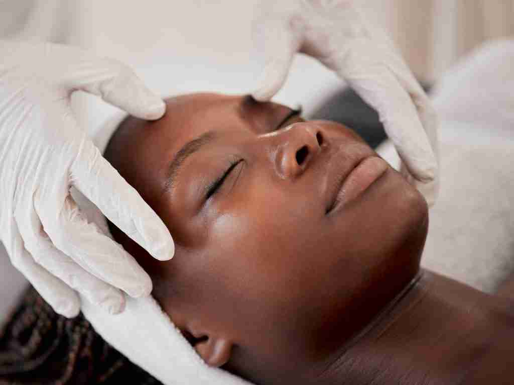 Client relaxing during a professional facial massage at a spa.